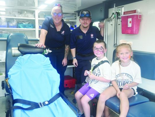 Five-yearold Emy Young and 6-year-old Dixie Harris pose for a photo in the ambulance with Paramedic Ashley Henderson and EMT Ryan Walls at Teague’s National Night Out. LOWER