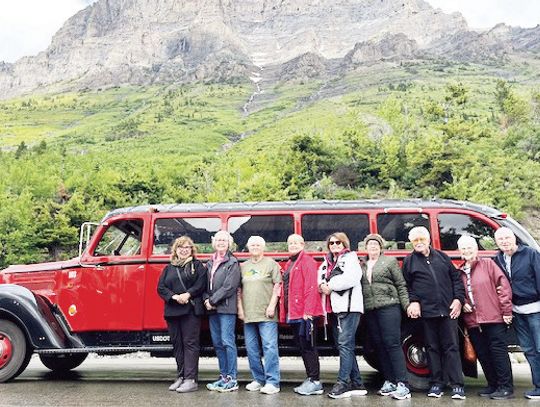 Standing in front of the jammer that transported the travelers along the Going-to-the-Sun road in Glacier National Park are Jovanka Mrdja (Tour Manager), Amy Kent, Jerri McBay, Amy Kent, Glynis Rosas, Cleo Burlingame, Stephen Burlingam, Amanda Burleson, Maurice Burleson. The mountain in th...